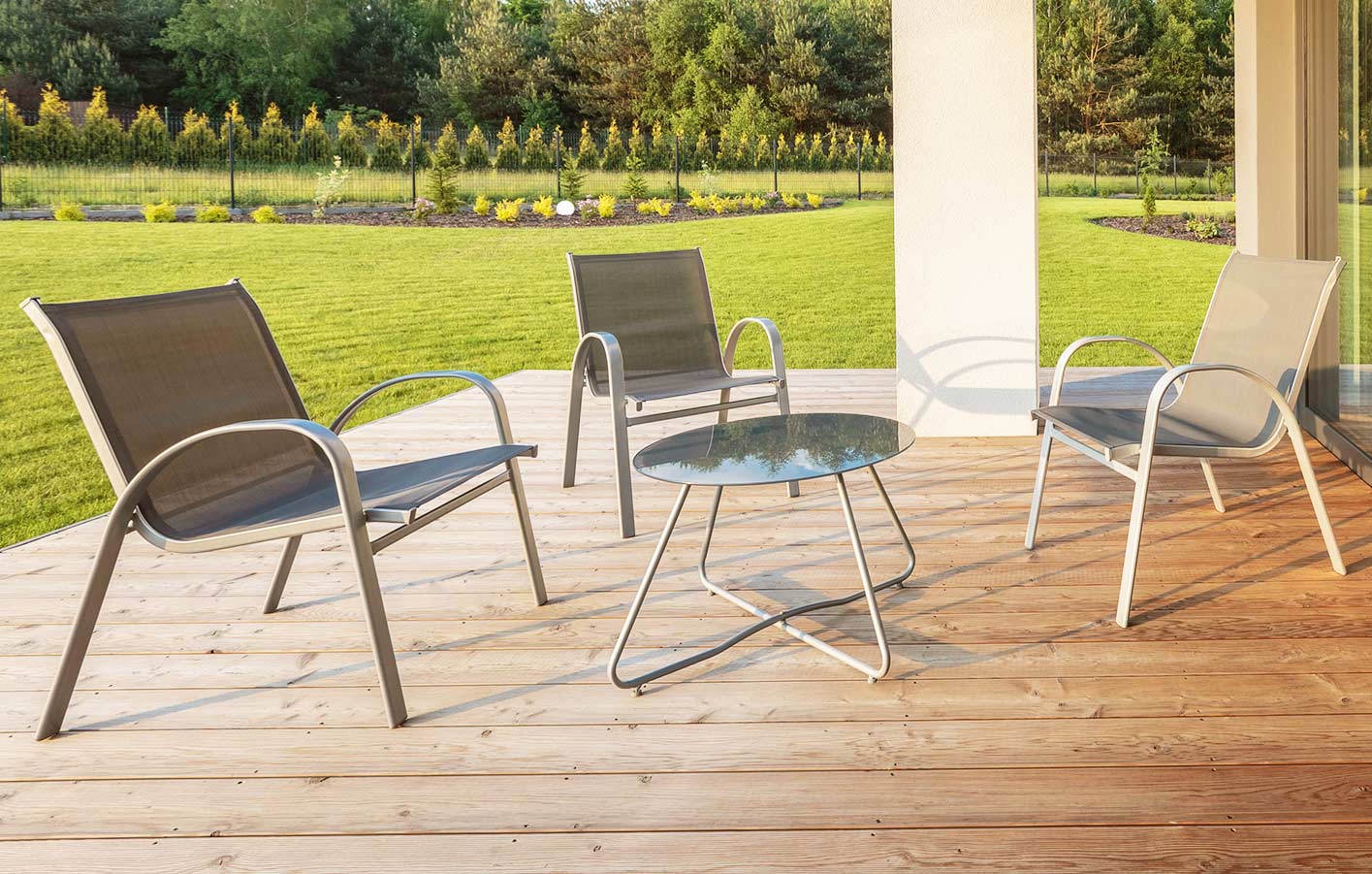 moderne Terrasse mit einfachen und modernen Terrassenmöbeln mit Blick in einen grünen Garten